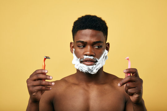 thoughtful man holding two razors and choosing one of them to shave his beard. right or left difficult choice.