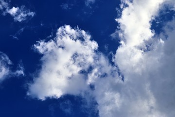 Beautiful fluffy white clouds covered in sunlight on a deep blue sky 