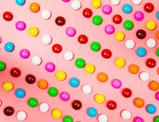 Colorful lollipop and different colored round candy. Top view pink pastel background