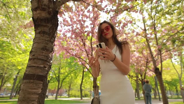 Woman make selfie photo in beautiful blossom summer park