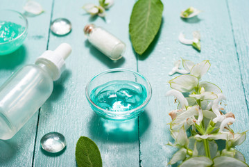 shampoo, shower gel, essential oil, pipette and clary on blue wood table