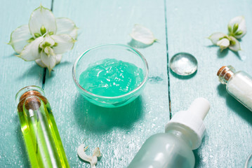 shampoo, shower gel, essential oil, pipette and clary on blue wood table