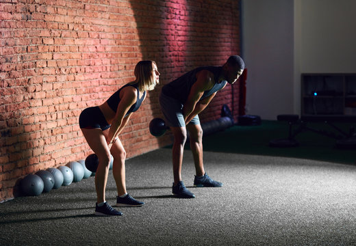 Sporty young interracial couple with dumbbells on red brick wall background - Powered by Adobe