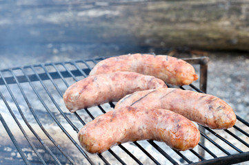 Pork sausages are roasted on the coals on the grill.
