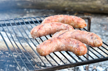 Pork sausages are roasted on the coals on the grill.