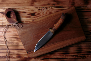 Hunting knife handmade from steel and wood handle. Stylish knife on old wooden background.