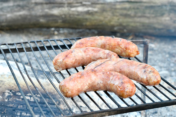 Pork sausages are roasted on the coals on the grill.