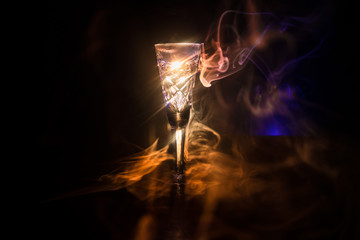 Closeup wine glass with fog at dark background. Beautiful glass with smoke and light.