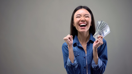 Excited asian woman with dollar banknotes, lottery winner, good fortune, luck