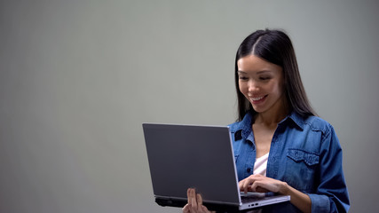 Smiling asian woman chatting on laptop, communicating with friends, new app