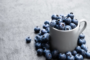 Cup full of fresh ripe blueberries on black stone background