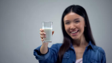 Fototapeta premium Cheerful woman showing glass of milk into camera, useful bacteria for health