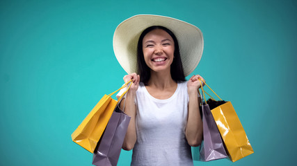 Extremely happy woman in white hat holding many paper bags, shopping addicted