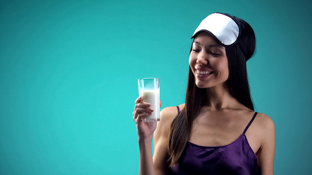 Smiling female looking at milk glass, beverage for better sleeping, calcium
