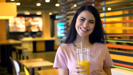 Beautiful female holding orange juice and smiling, fresh bar cocktails, vitamin