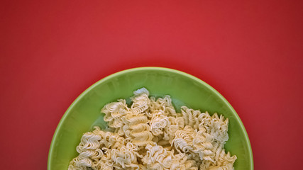 Fast food noodles in green plate on bright background, unhealthy nutrition