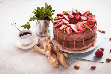 Strawberry cake decorated with mint leaves, cookies and a Cup of coffee on a light background. Copy space