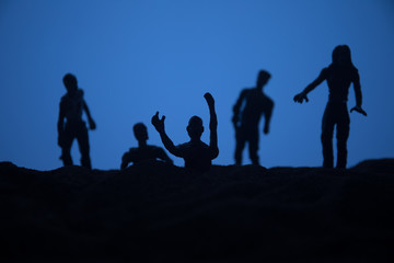 Silhouette some zombies on the cemetery walking around at sunset. Selective focus