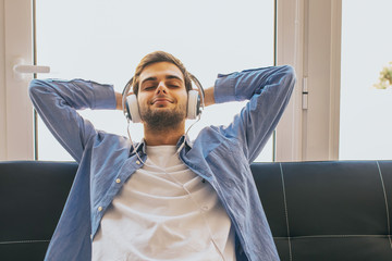 young man listening to music at home with headphones