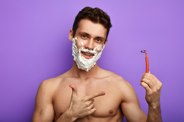 cheerful nacked man holding a disposable razors with a single blade. fist helper for real men.