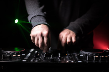 DJ Spinning, Mixing, and Scratching in a Night Club, Hands of dj tweak various track controls on...