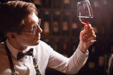 Experienced sommelier possessing not only wine etiquette but also wine tasting skills enjoying taste and flavor of noble beverage.