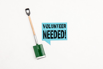 Volunteer Needed concept,  shovel for digging  and sign with text. Speech bubble