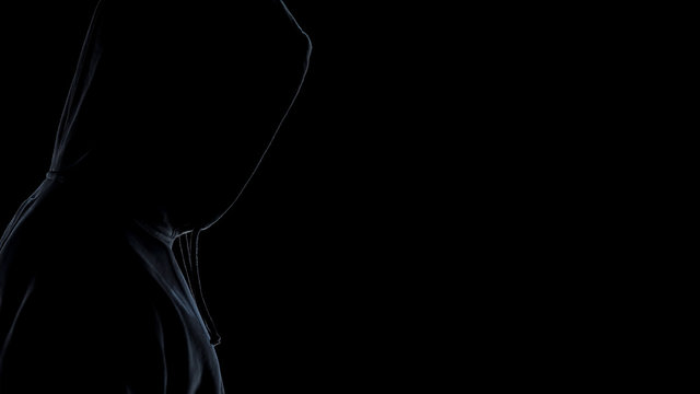 Side view of hooligan silhouette standing against dark background, close up