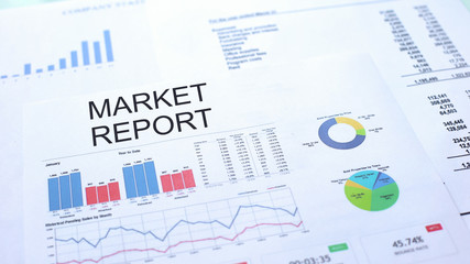 Market report lying on table, graphs charts and diagrams, official document