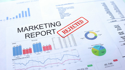 Marketing report rejected, hand stamping seal on official document, statistics