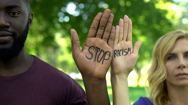 Afro-american man and caucasian woman showing palms with stop racism phrase