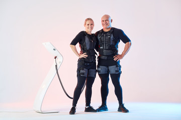 man and woman in electric muscular suit are working out, looking at the camera. full length photo. active life, leisure concept