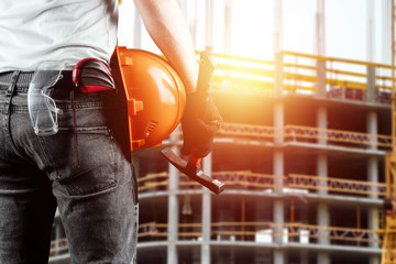 A builder, an architect holds in his hand a construction helmet against the background of a construction site, a tape measure. Concept architecture, construction, engineering, design, repair.