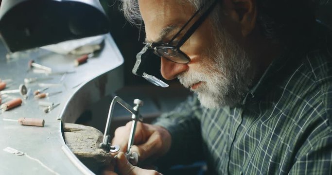 Slow motion of experienced goldsmith working on a handmade jewelry bracelet chain of precious metal white gold in a workshop.Shot in 8K.Concept of jewelry, luxury,goldsmith,gold,silver,precious metals