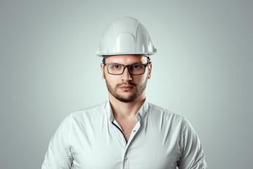 Portrait of a man in a construction white helmet on a light background. Concept architecture, construction, engineering, design, repair. Copy space