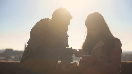 Young couple scrolling phones on rooftop, navigation for tourists, geolocation