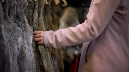 Young female looking at fur coats at street market, shopping and consumerism