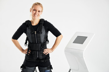 pleasant happy woman standing in front of the EMS machine. ems fitness. perfect training. hobby,...