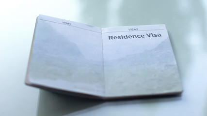 Residence visa, opened passport lying on table in customs office, travelling