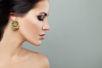 Young woman face with fashion jewelry earrings with green gem and diamond portrait