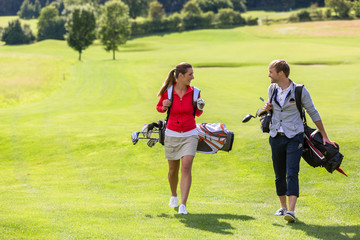 Obraz premium Couple carrying golf bag while walking on golf course