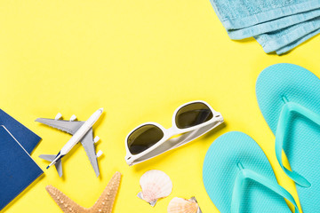 Blue flip flops, sunglasses, passport and starfish on yellow background.