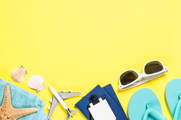 Blue flip flops, sunglasses, passport and starfish on yellow background.