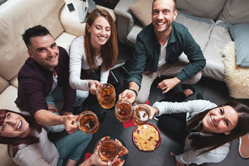 Happy group of friends drinking beer and eating pizza