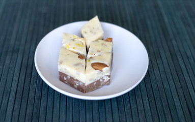Oriental dessert halva with pistachio, almond, cashew nuts, peanut, walnut  on a  plate. Image. Healthy food. closeup of sweets from Iran popular  Turkish Delight. Isolated on background