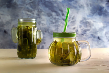 Cucumber pickle in a jar with a lid and tube on wooden table. Close-up