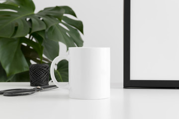 Mug mockup with workspace accessories and a monstera plant.