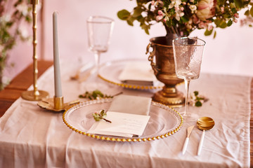 Festive table decor. Golden cutlery. With different natural colors and flowers. Garnet. Luxury wedding, party, birthday. View from above. Gold, pink. Candles