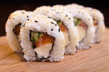 Sushi rolls with salmon and cheese. Japanese traditional cuisine. Rice with seafood. Menu maki rolls on a black background