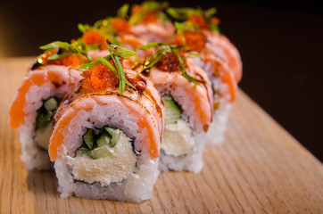 Beautiful sushi rolls with tuna on a wooden plank. Japanese sushi with fish in the Ukrainian seafood restaurant. Menu rolls on a black background